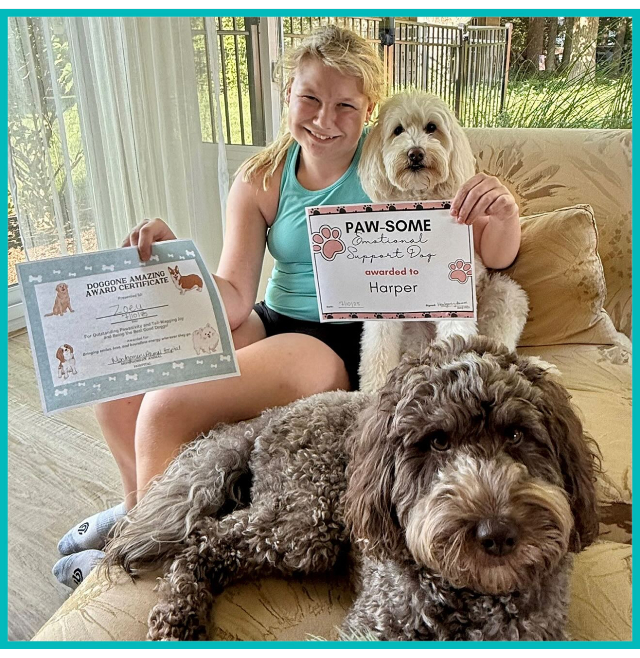 A smiling girl sitting indoors holds two certificates, with a white dog sitting behind her and a brown dog lying in front. Sunlight streams through large windows in the background.